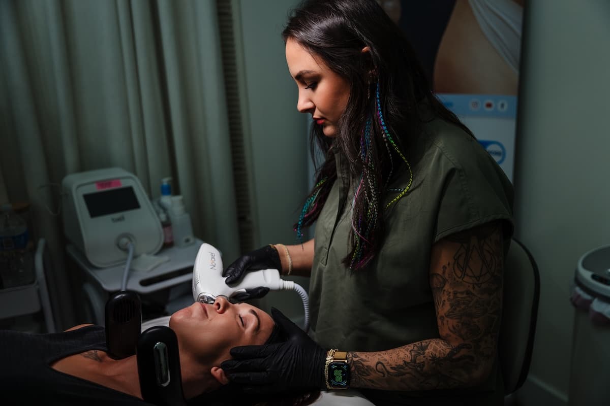 Laser specialist at Wichita Laser Clinic guiding the Tixel handpiece over a reclining client's face during a skin rejuvenation treatment