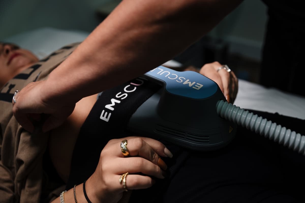 Close-up of an EMSCULPT NEO applicator strapped over a client's abdomen during a 30-minute body sculpting treatment