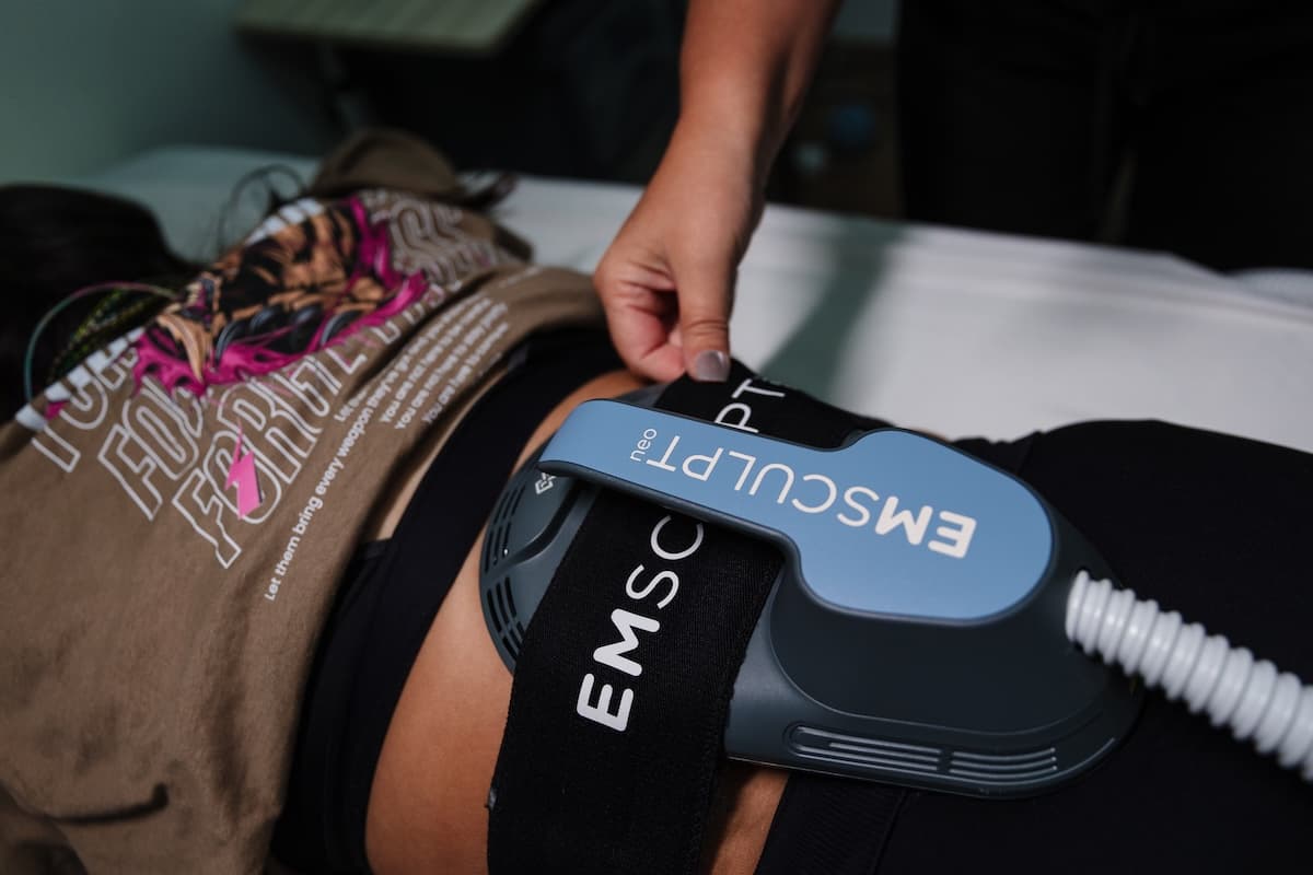 Specialist at Wichita Laser Clinic securing an EMSCULPT NEO applicator belt over a client's stomach before a body sculpting session